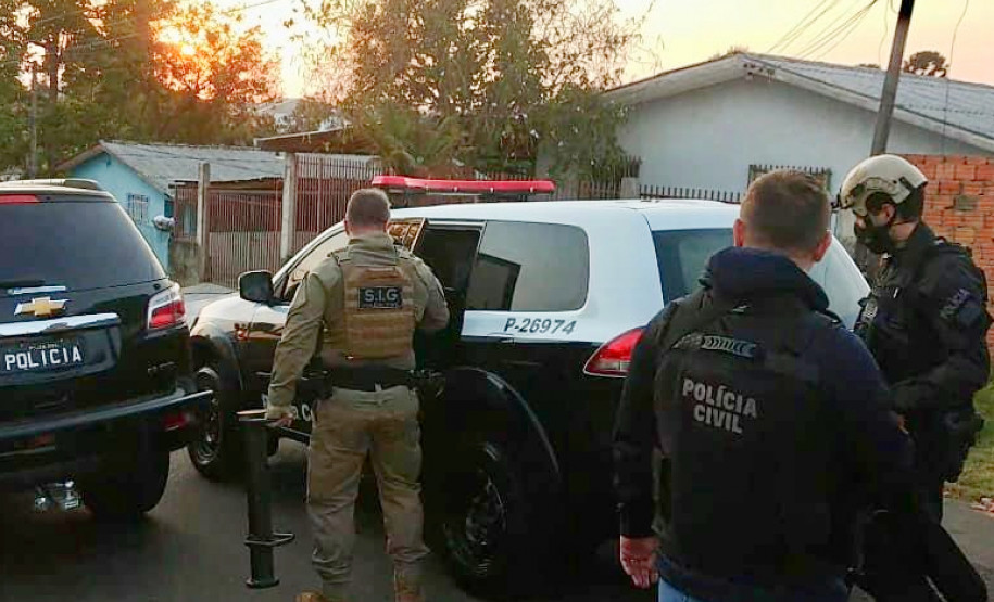 Policiais civis ao lado de viaturas