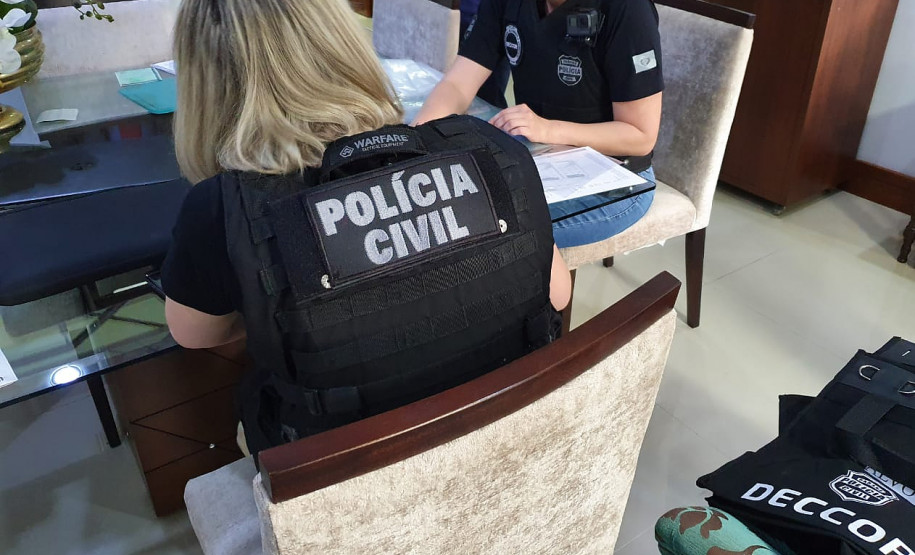 Policiais civis à mesa, preenchendo documentos