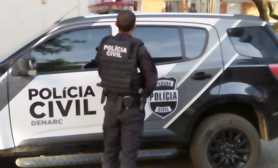 Policial civil ao lado de viatura