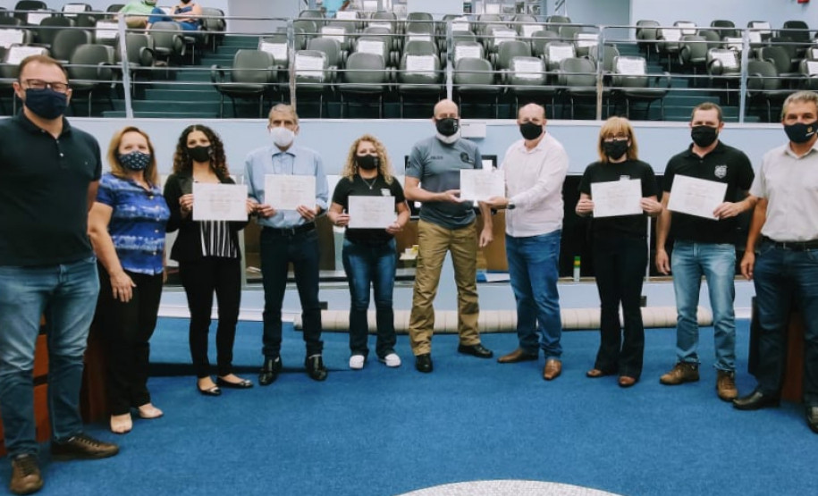 Homenageados posando para foto, segurando o certificado