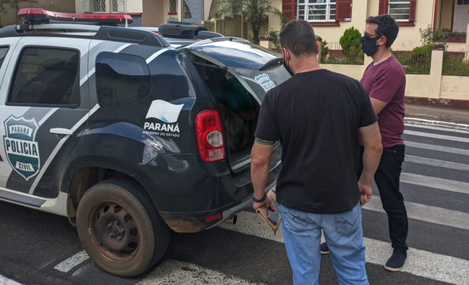 Policiais civis colocando suspeito na viatura
