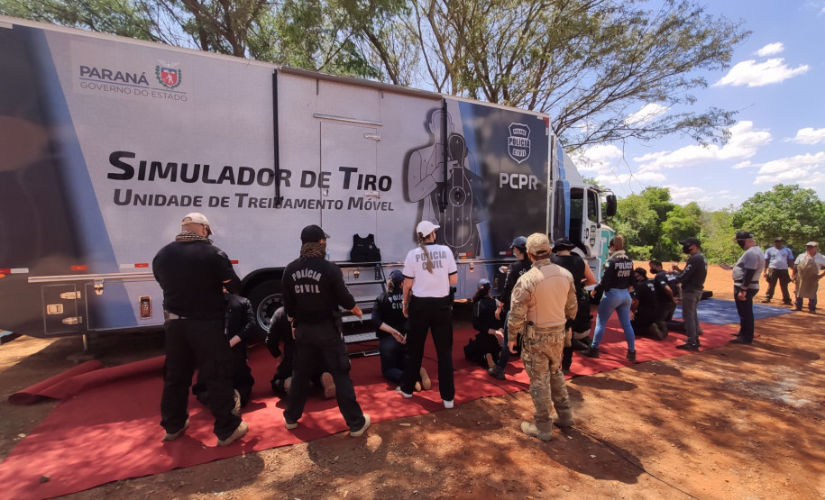 Policiais civis observam técnicas de algemamento, ao lado de caminhão simulador de tiro