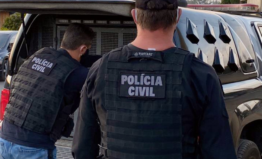 Dois policiais civis ao lado de viatura