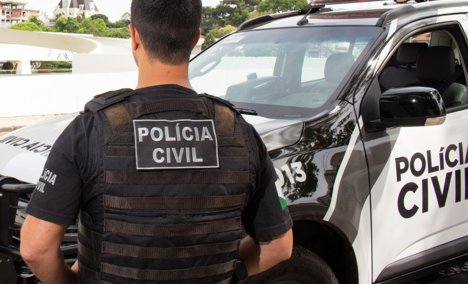 Policial civil ao lado de viatura