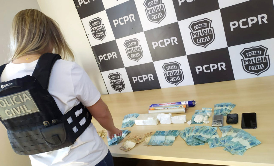 Policial civil de costas organizando materiais apreendidos sobre uma mesa