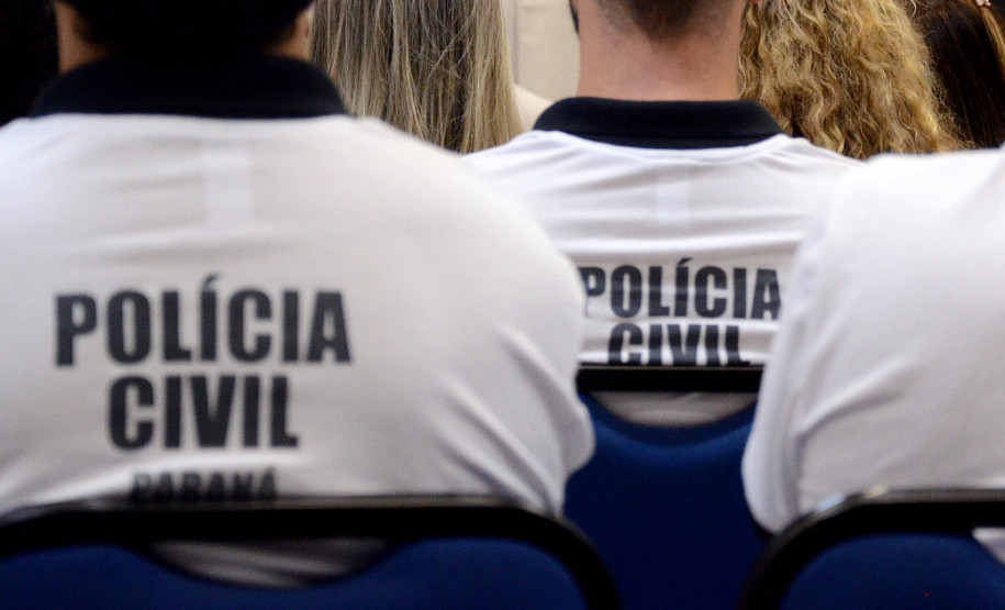 Policiais civis de costas, sentados, recebendo instruções