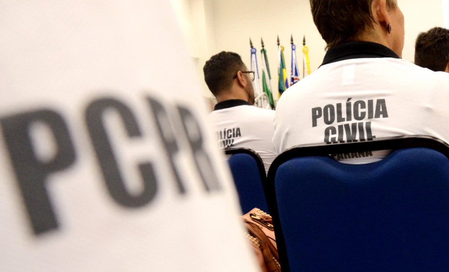 Policiais civis de costas, sentados. Em primeiro plano, nome PCPR.
