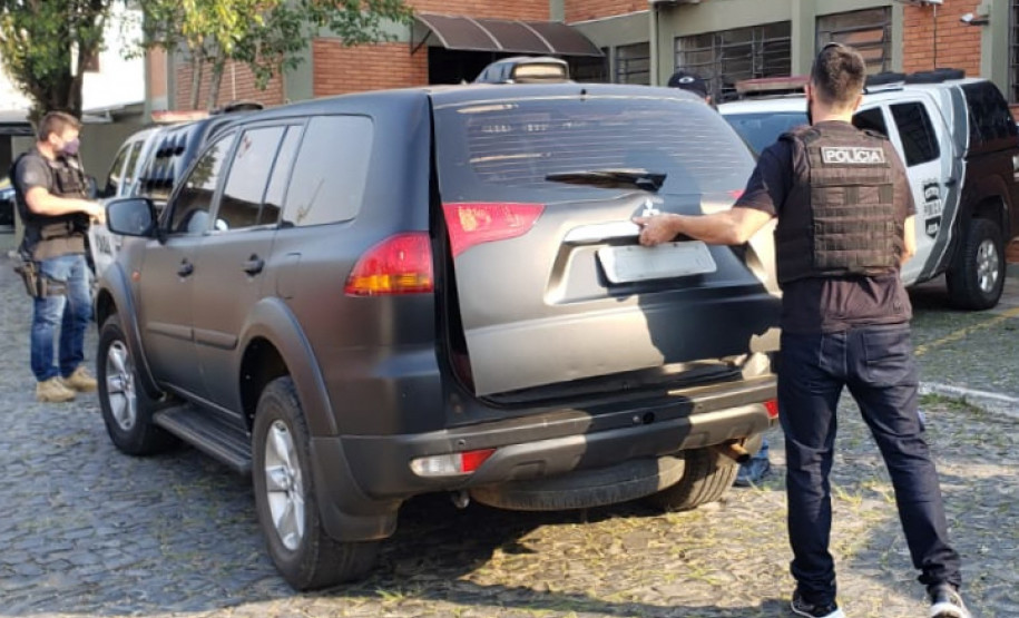 Policial civil fechando tampa de porta-malas de viatura
