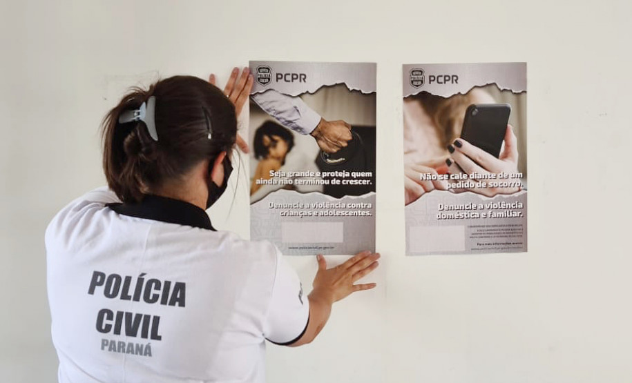 Policial civil fixando cartaz na parede