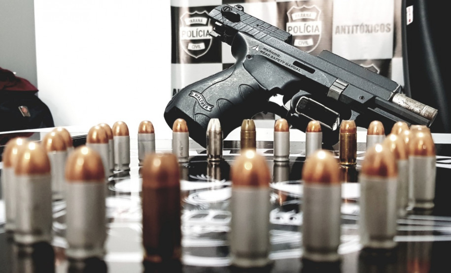 Diversos projéteis e uma arma sobre uma mesa