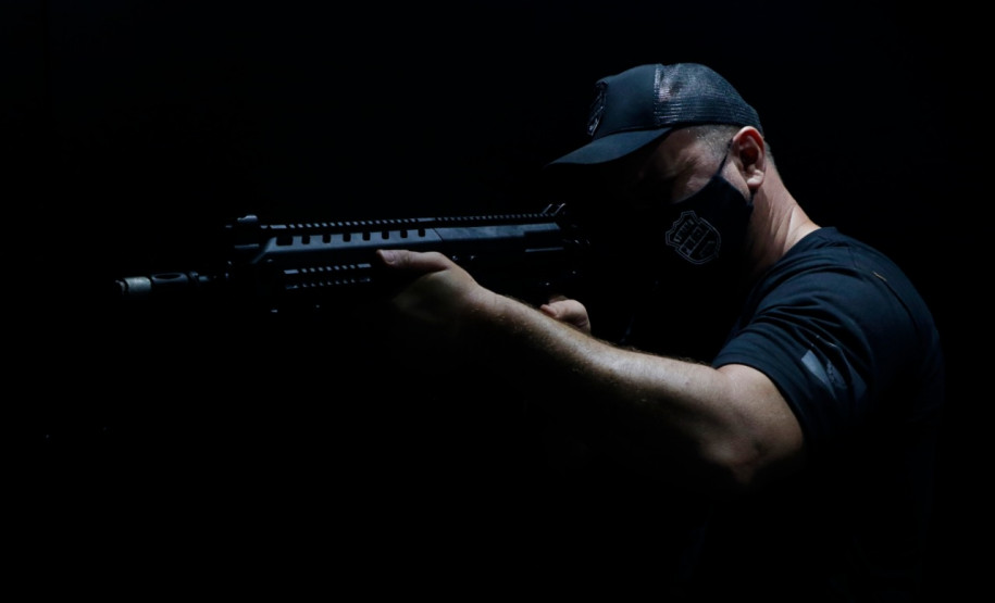 POlicial civil apontando fuzil em lugar escuro