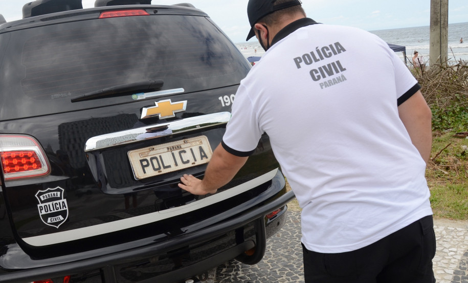 Policial civil fechando tampa do porta-malas de viatura