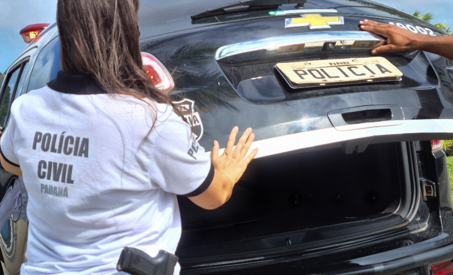 Policiais civis fechando tampa de porta-malas de viatura
