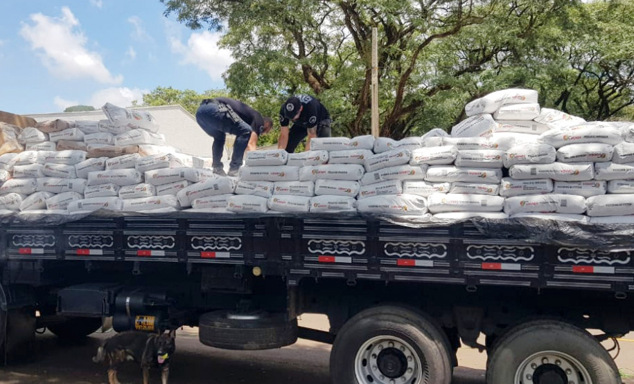 Policiais civis em cima de carroceria de caminhão carregado com droga