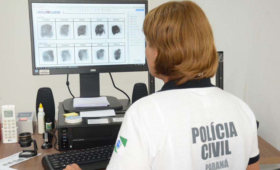 Policial civil analisando digitais em tela de monitor