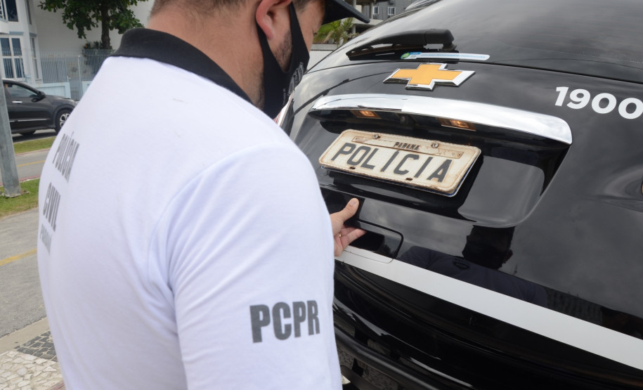 Policial civil fechando o porta malas da viatura