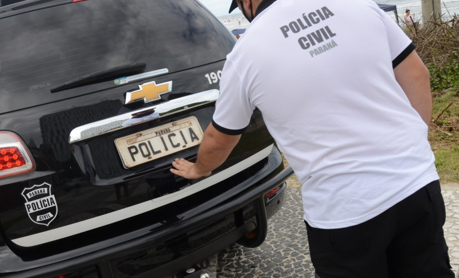 Policial civil fechando tampa do porta-malas de viatura