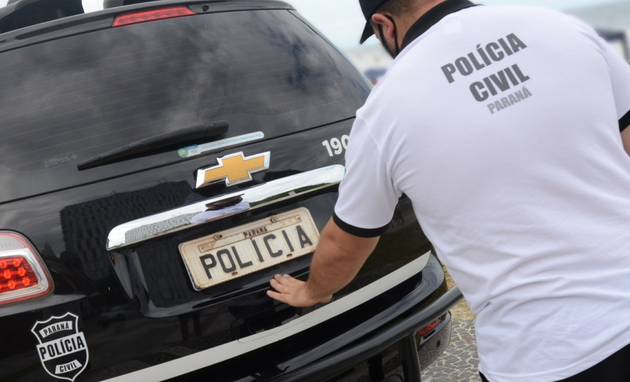 Policial civil fechando tampa do porta-malas de viatura