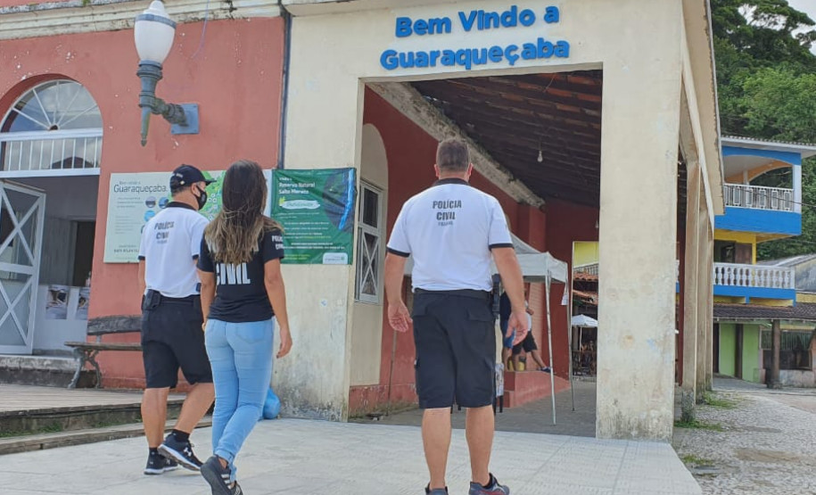 Três policiais civis de costas, andando.