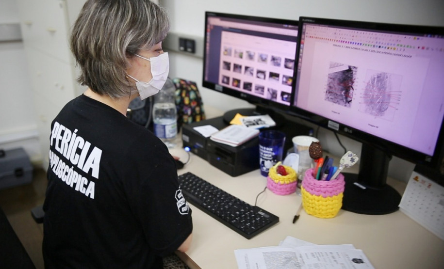 Policial civil analisando digitais em tela de monitor