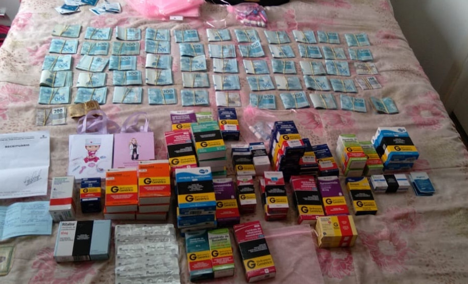 Dezenas de caixas de remédio e cédulas de dinheiro sobre uma cama