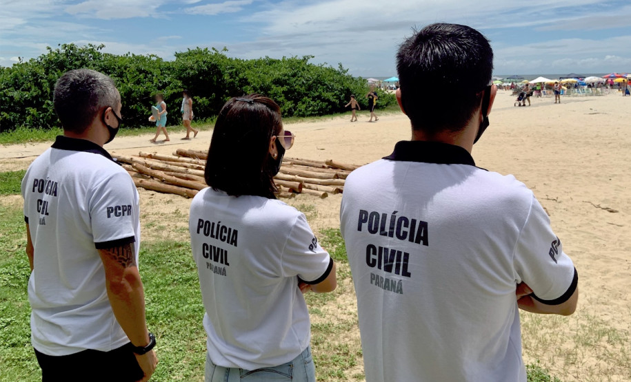 Três policiais civis observando movimento no litoral
