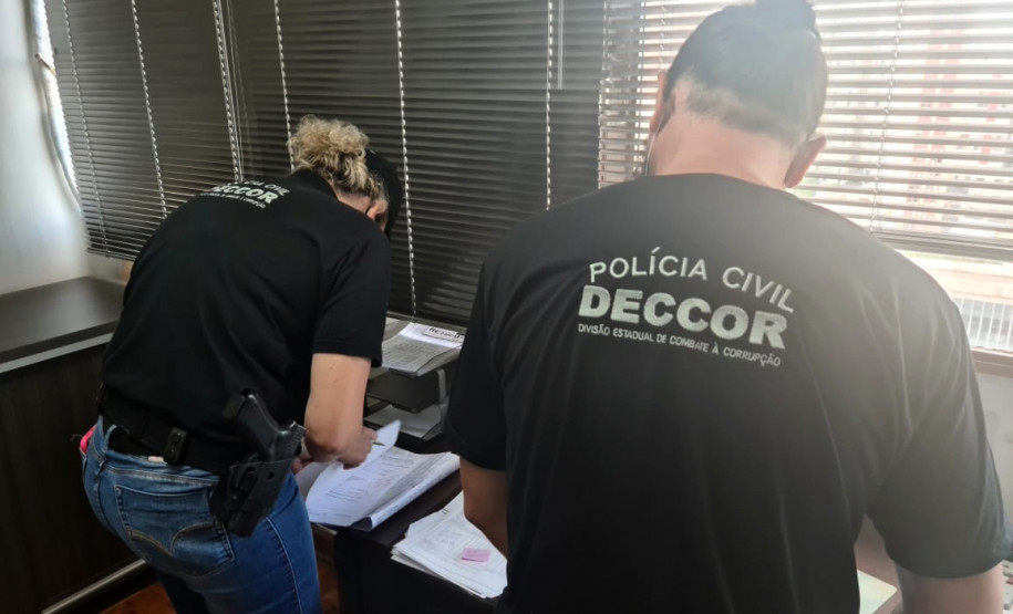 Dois policiais civis analisando documentos