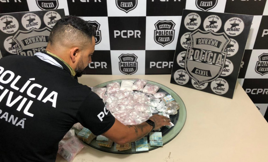 Policial civil organizandosobre uma mesa material apreendido