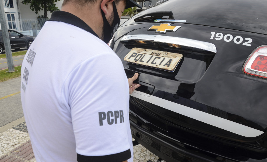 Policial civil fechando tampa do porta-malas de viatura