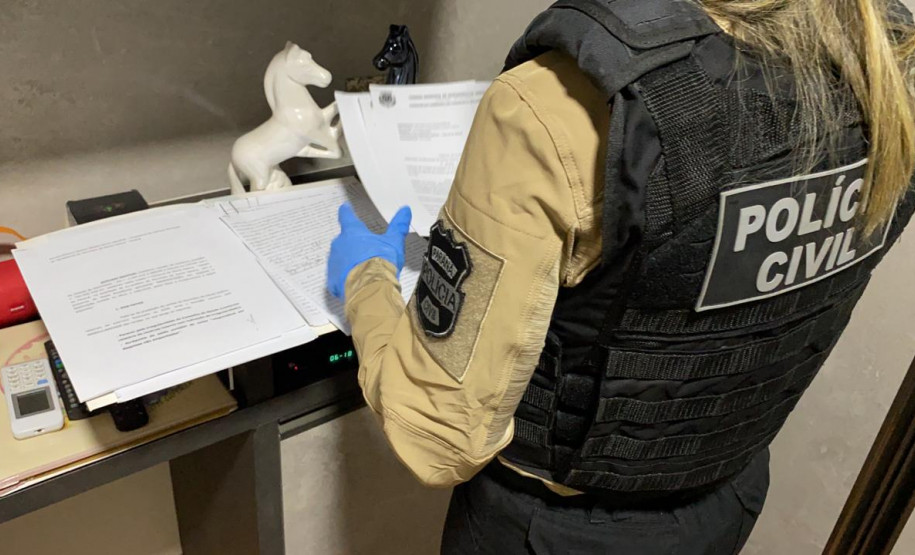 Policial civil em pé, analisando documentos