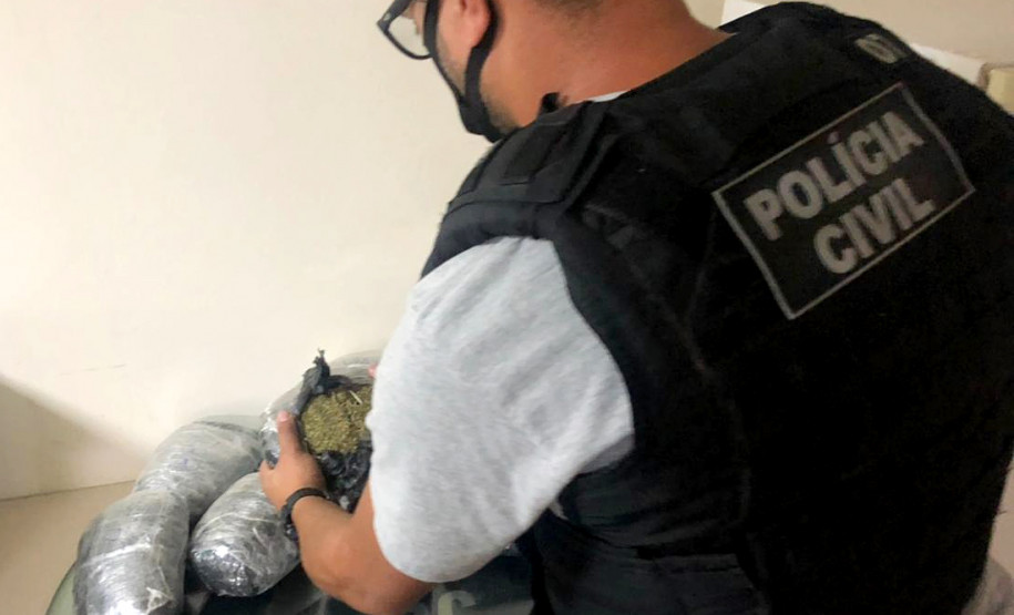 Policial civil abrindo pacote de skunk sobre uma mesa