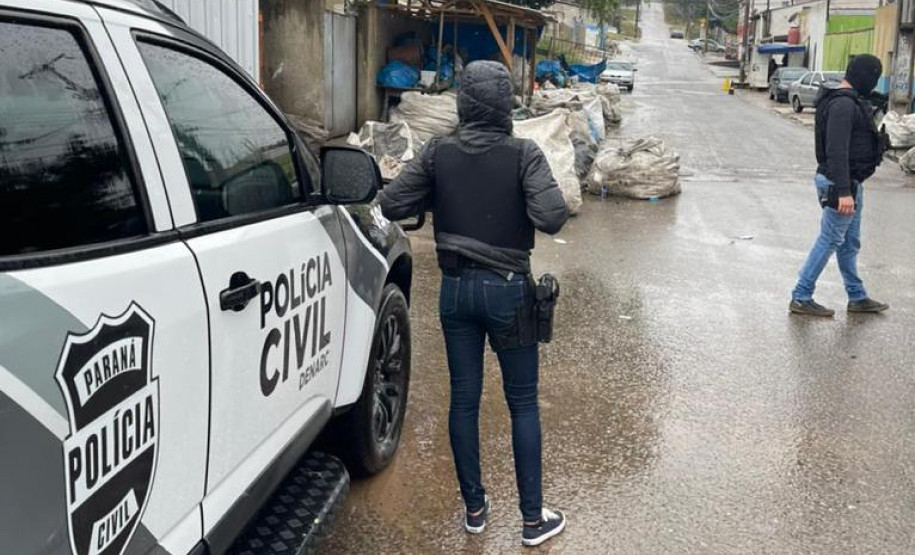 Policiais civis ao lado de viatura investigando o local