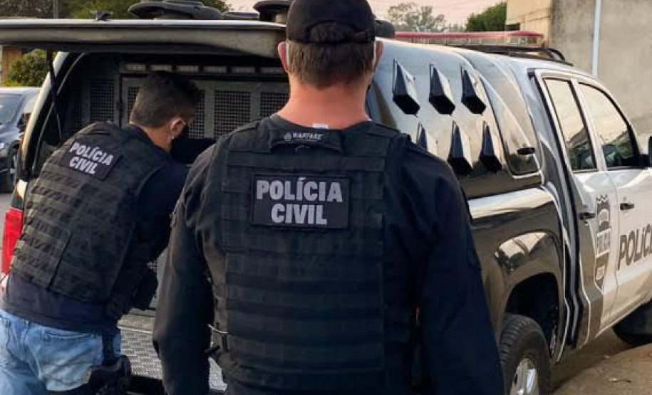 Dois policiais civis ao lado de viatura