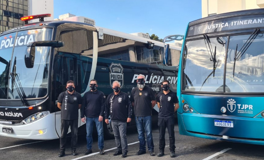 Policiais civis posando para foto entre ônibus da PCPR e TJ