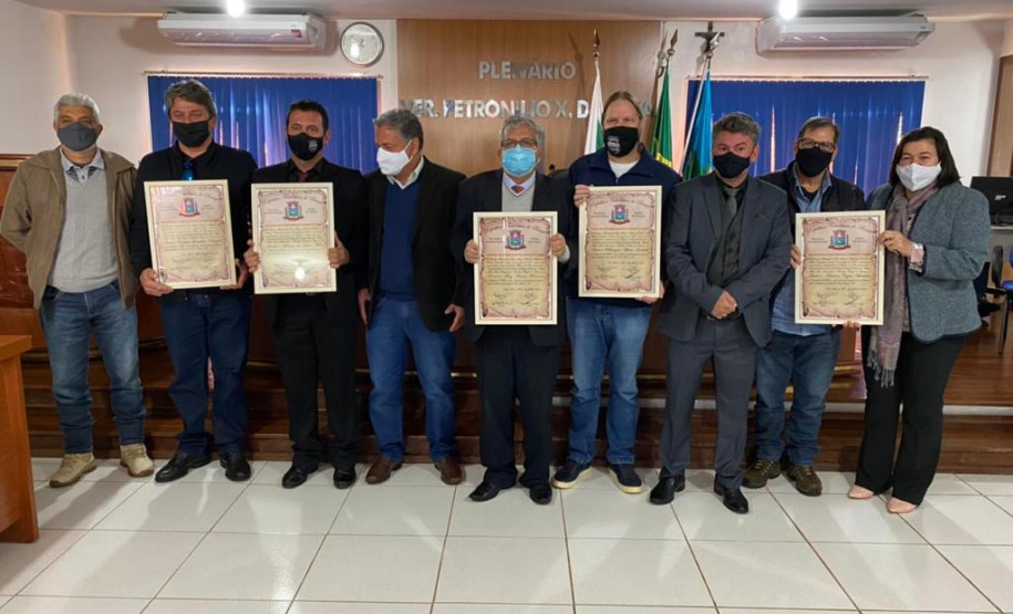 Homenageados e envolvidos no evento posando para foto e exibindo certificados