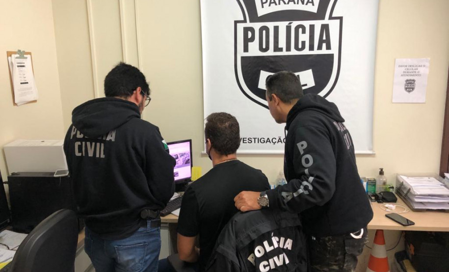 Três policiais civis analisam imagem na tela do computador