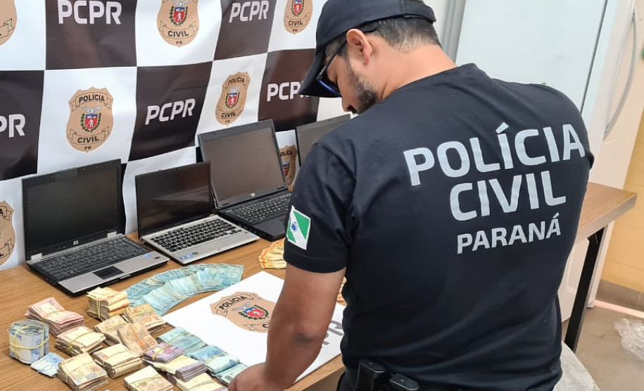 Policial civil organiza sobre uma mesa dinheiro recuperado