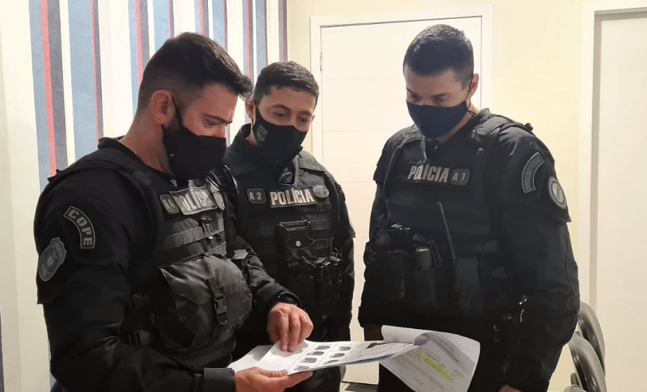 Três policiais civis verificando documentos