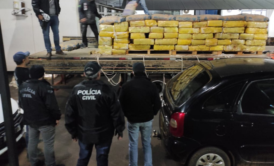 Policiais civis observando e descarregando caminhao com as drogas