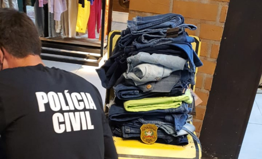 Policial civil, de costas, analisando mercadoria da loja