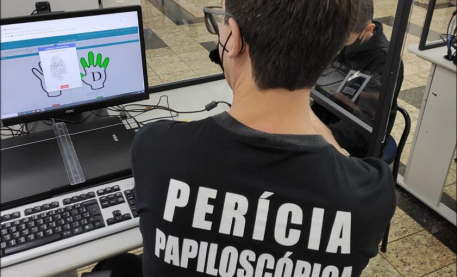 Policial civil de costas, recolhendo digital