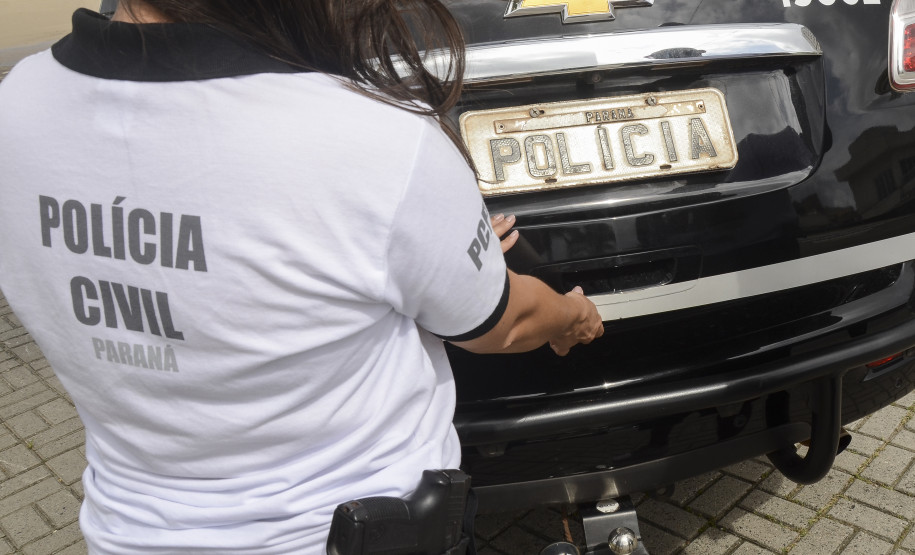 Policial civil fechando tampa de porta-malas de viatura