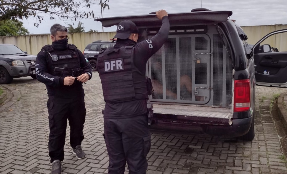 Policiais civis com presos em viatura