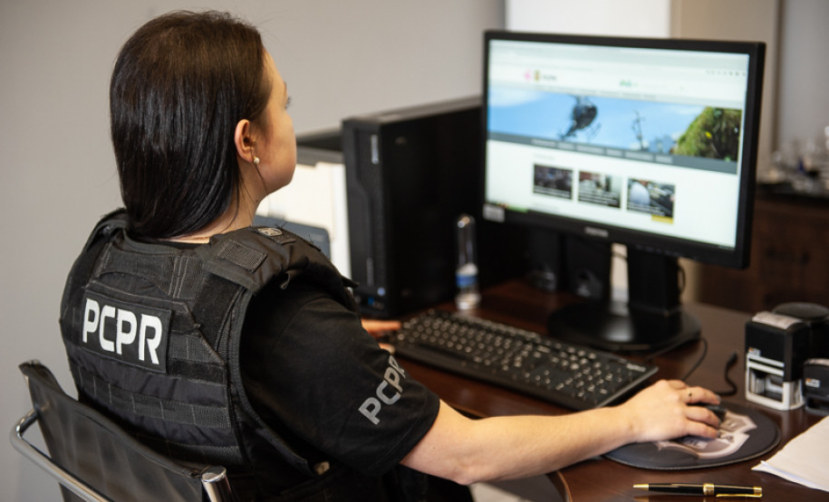 Policial civil feminina aparece acessando website da instituição em computador