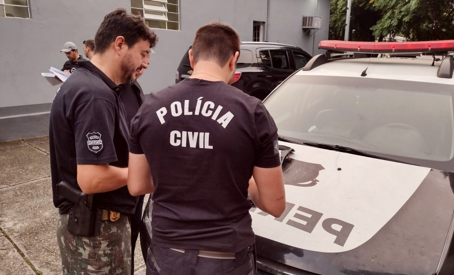 Dois policiais civis verificando material apreendido