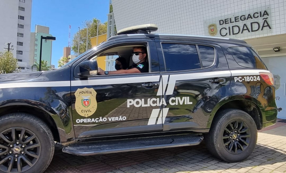 Policiais civis no interior de viatura em frente à delegacia cidadã