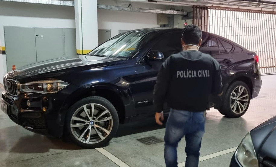 Policial civil de costas observando veículo de luxo estacionado