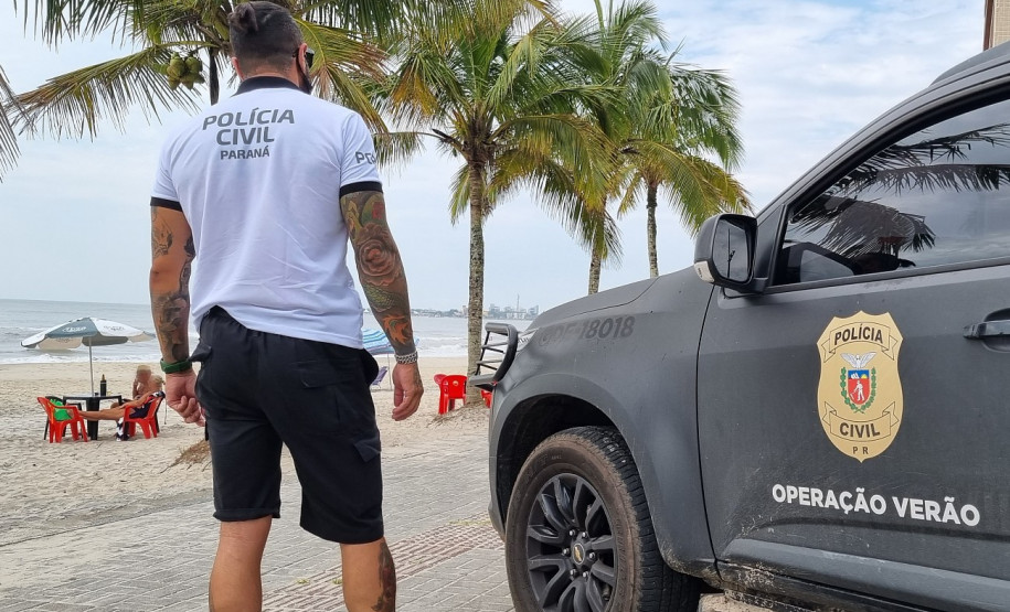 Policial civil ao lado de viatura observa o movimento dos veranistas