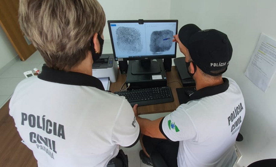 Dois policiais civis analisando impressões digitais