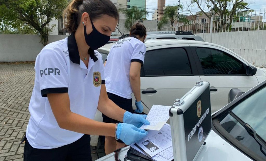 Duas papiloscopistas recolhendo impressões digitais em automóvel